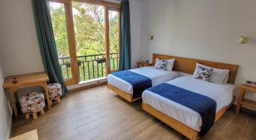 a bedroom with two beds and a balcony with a window at Margarit Boutique Hotel in Mindo
