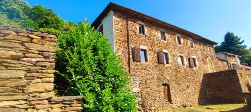 a large brick building with a stone wall at L'Art des Choix in Saint-Jean-de-Pourcharesse