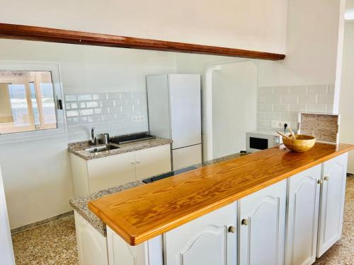 a kitchen with white cabinets and a wooden counter top at Famara Frontsea house in Famara