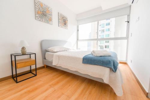 a white bedroom with a bed and a window at Boutique Apartments Panamá Marbella in Loma del Naranjo