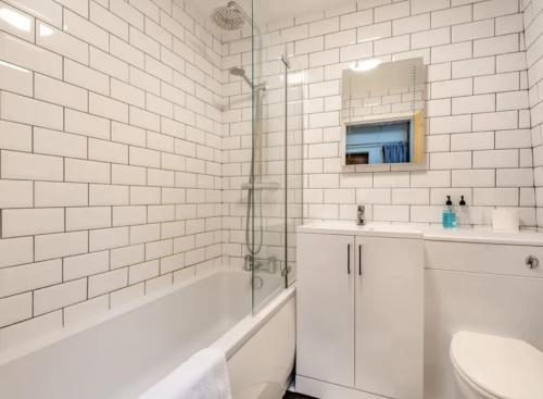 a white bathroom with a tub and a sink and a toilet at Curly Tail Accommodation in Bishops Castle