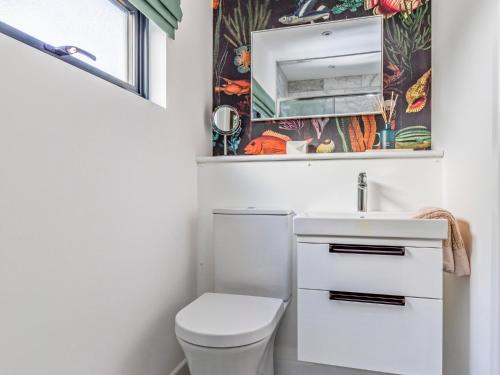 a bathroom with a toilet and a sink and a mirror at Pass the Keys Charming Bosham Garden Lodge in Chichester