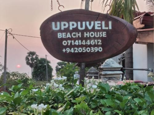 a sign for a beach house in a garden at UPPUVELI BEACH HOUSE in Trincomalee