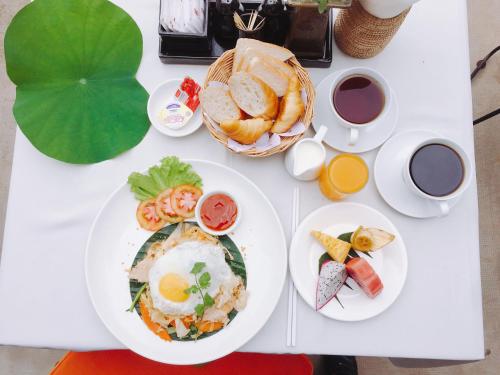 a white table with plates of food and cups of coffee at Home Indochine d'Angkor Hotel in Siem Reap
