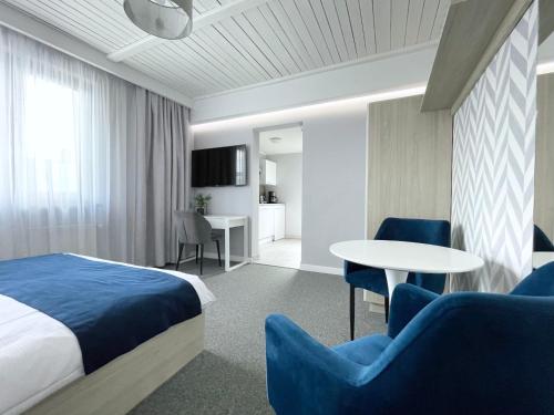 a hotel room with a bed and a table and chairs at Willa Lazur ADULTS ONLY in Międzyzdroje