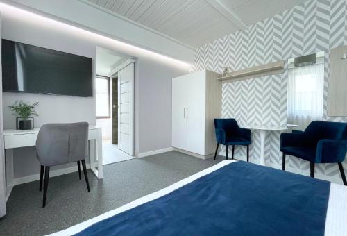 a hotel room with a bed and chairs and a television at Willa Lazur ADULTS ONLY in Międzyzdroje