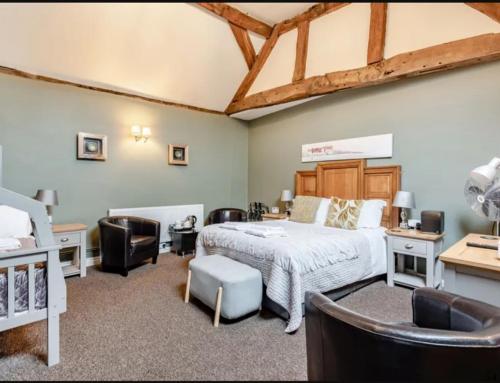 a bedroom with a bed and chairs in a room at Curly Tail Accommodation in Bishops Castle