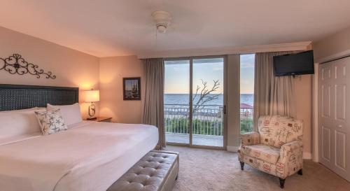a bedroom with a bed and a chair and a window at Villas by the Sea Resort & Conference Center in Jekyll Island