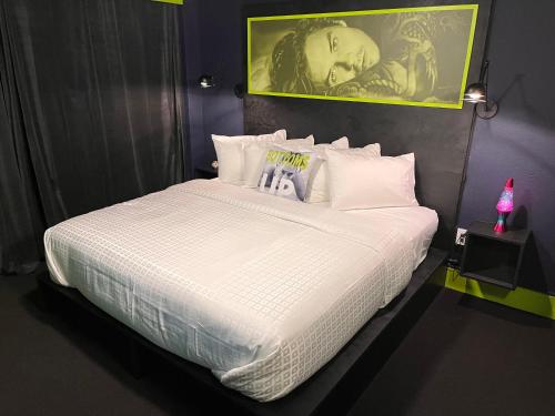 um quarto com uma cama grande com lençóis brancos e almofadas em Mari Jean Hotel - Adults Only Gay Hotel em St. Petersburg