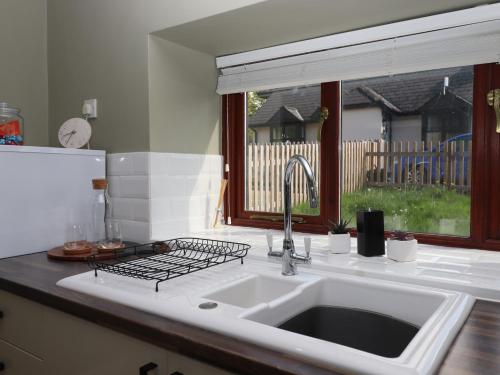 um balcão de cozinha com um lavatório e uma janela em Rose Cottage at Treaslake Farm em Honiton