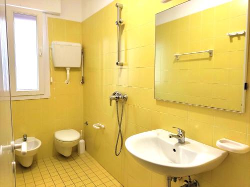 W łazience znajduje się umywalka, toaleta i lustro. w obiekcie Green Holiday Village with Pool w Bibione