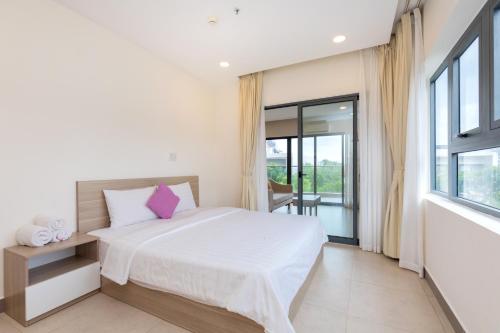 a bedroom with a white bed and a large window at Căn hộ nghỉ dưỡng Aria Vũng tàu in Xa Thang Nhut