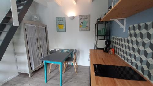 a small blue table in a room with a staircase at Les Appartements du 104 in Saint-Jean-de-Monts