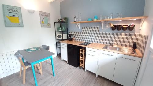 a small kitchen with a table and a table and a counter at Les Appartements du 104 in Saint-Jean-de-Monts