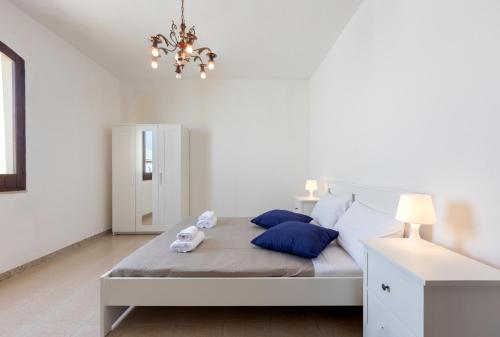 een slaapkamer met een bed met blauwe kussens en een kroonluchter bij Villa Ninnedda in SantʼAndrea