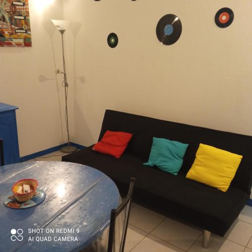 un canapé noir avec des coussins colorés à côté d'une table dans l'établissement La maison du paradis, à Bellegarde