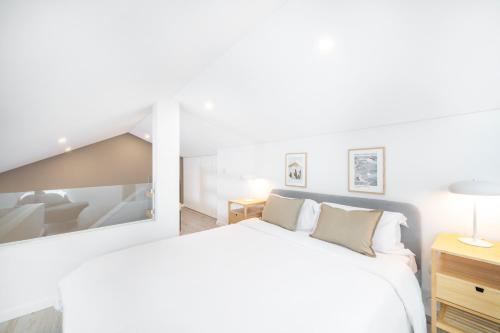 a white bedroom with a bed and a mirror at Lisbon Oriente Suites by Olala Homes in Lisbon
