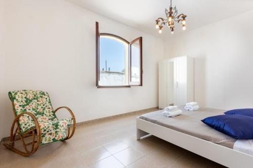 een slaapkamer met een bed, een stoel en een raam bij Villa Ninnedda in SantʼAndrea