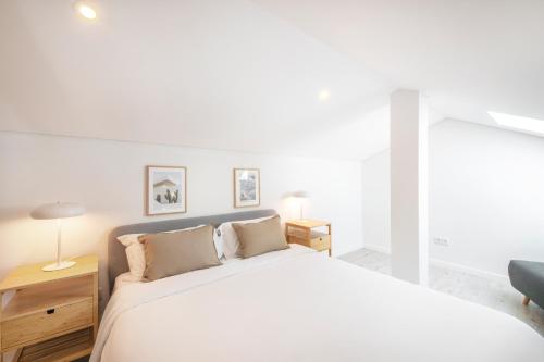 um quarto branco com uma cama grande e uma cadeira em Lisbon Oriente Suites by Olala Homes em Lisboa
