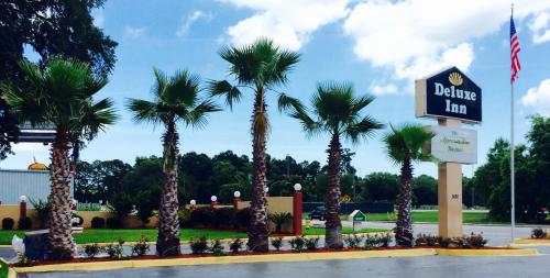 a drive in inn with palm trees and a sign at Deluxe Inn - Savannah in Savannah