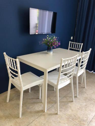 a white table with two chairs and a vase with flowers at Blue Apartment in Gonio