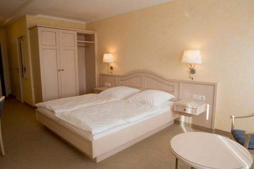 a bedroom with a white bed and a table at Landhaus Sterdebüll in Bordelum