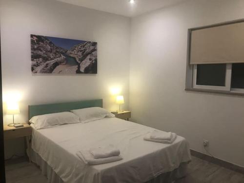 a bedroom with a white bed with two lamps and a picture at Seafront, 2 bed apartment in quiet central area in Pembroke