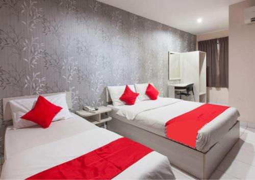 a bedroom with two beds with red pillows at Hotel Pulai Ipoh in Ipoh
