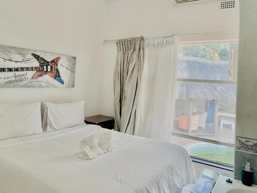 um quarto com uma cama branca e uma janela em Homeinn Guesthouse em Nelspruit