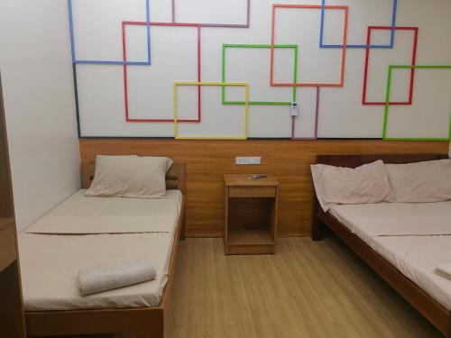 two beds in a room with a painting on the wall at Mansion 8 Residences in Roxas City