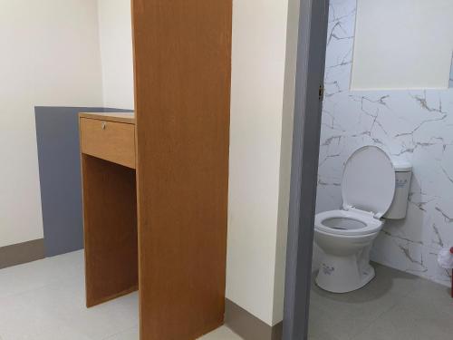 a bathroom with a toilet and a wooden door at Mansion 8 Residences in Roxas City
