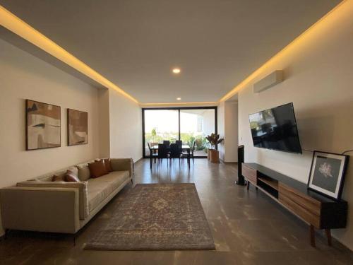 a living room with a couch and a flat screen tv at Depa enfrente del Hotel RIU @serra in Guadalajara