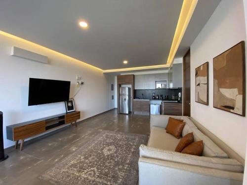 a living room with a couch and a flat screen tv at Depa enfrente del Hotel RIU @serra in Guadalajara