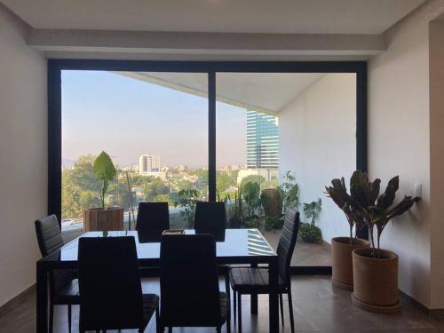 a dining room with a table and chairs and a large window at Depa enfrente del Hotel RIU @serra in Guadalajara