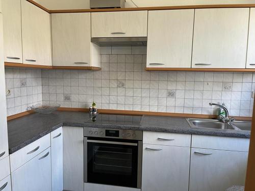 a kitchen with white cabinets and a stove and a sink at Weingut Sparrmühle Clarissa und Werner Manz GbR in Undenheim