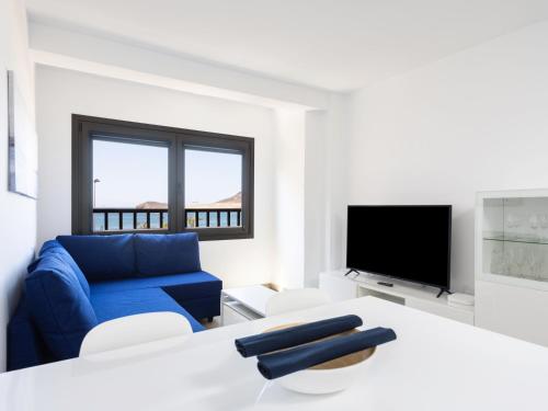a living room with a blue couch and a tv at Live Medano Casanova frente a la playa in El Médano