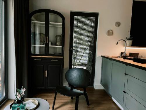 a kitchen with a black cabinet and a chair at Camping Milk in Usmenieki