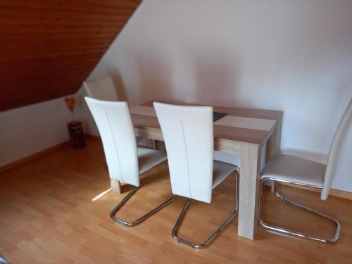 a dining room table with two white chairs at Ferienwohnung Siggi in Hardt