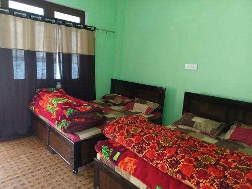 two beds in a room with green walls at Aditya guest House and restaurant in Trijugi Nārāyan