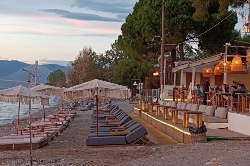 a row of lounge chairs and umbrellas on a beach at You & Me, near the sea and Patras University in Patra