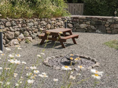 a picnic table in a garden with a stone wall at No 4 The Shippon in Llangefni
