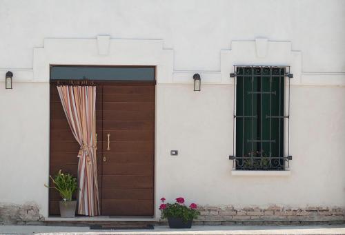 PegognagaにあるB&B Casa Pascoloneの窓とカーテン付きの木製ドア