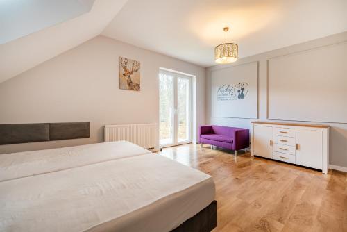 sypialnia z dużym łóżkiem i fioletowym krzesłem w obiekcie Dom Na Skraju Mazur w Olsztynie