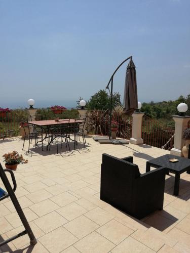 a patio with a table and chairs and an umbrella at Villa Etna Masi' in Milo