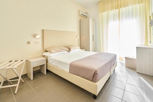 a bedroom with a bed and a desk and a window at Hotel Villa Perazzini in Rimini