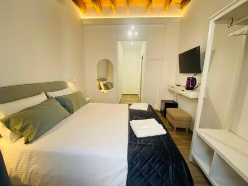 1 dormitorio con 1 cama blanca grande y TV en Cinque Terre Memory Affittacamere, en La Spezia