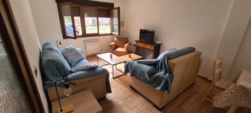 a living room with two chairs and a table at Apartamentos Casa de los Ramos in Vinuesa