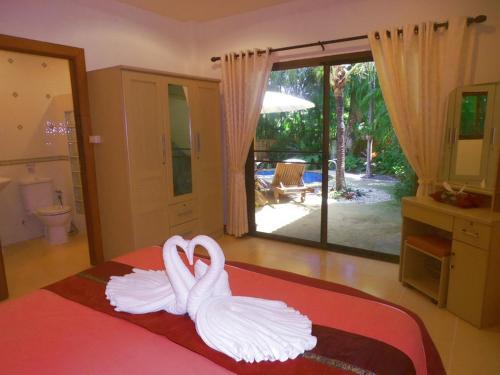 Dos cisnes blancos están sentados en una cama en una habitación en Coconut Paradise Holiday Villas, en Rawai Beach