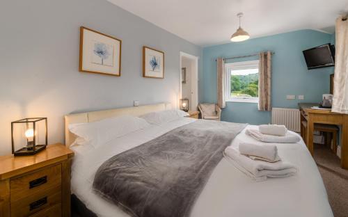 a bedroom with a bed and a desk and a window at Bower House Inn in Eskdale