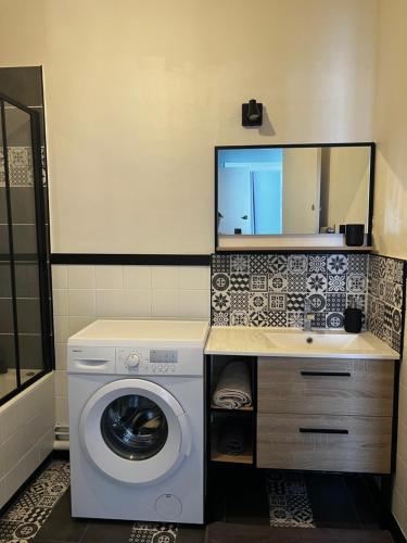 y baño con lavadora y espejo. en Douai 2: joli appartement face à la gare, en Douai